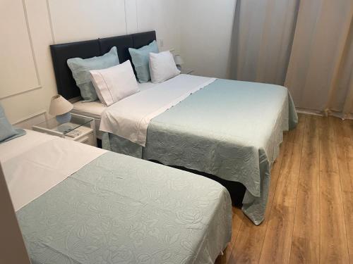 two beds in a small room with wooden floors at Suíte no Jardim Guedala in Sao Paulo