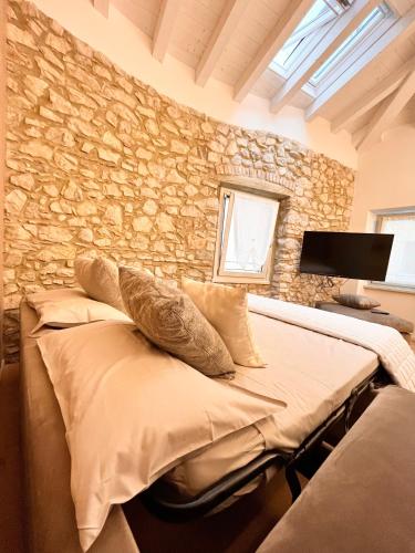 a bedroom with two beds and a stone wall at Ca' Filipet in Torri del Benaco