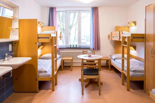 um quarto com beliches, um lavatório e uma mesa em Jugendherberge Hamburg Horner Rennbahn em Hamburgo