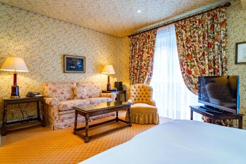 a hotel room with a bed and a couch and a television at Hotel Stadt Hamburg in Westerland (Sylt)