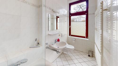 ein weißes Badezimmer mit einem Waschbecken und einem Spiegel in der Unterkunft traumhafte Jugendstilwohnung Gohlis in Leipzig