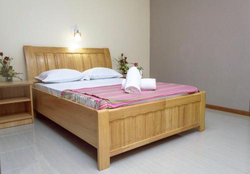 um quarto com uma cama de madeira e toalhas em Vintage Lodge em Quatre Bornes