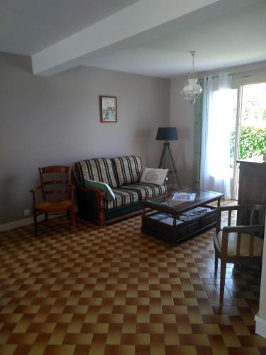 a living room with a couch and a table at Grande Maison de plain pied avec jardin arboré. in Champignelles