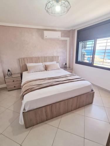 um quarto com uma cama grande e uma janela em Appartement Sable Rose em Al Hoceïma