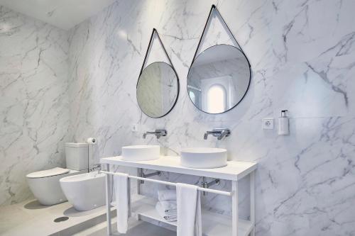 a white bathroom with two sinks and two mirrors at Gran Sol in Zahara de los Atunes