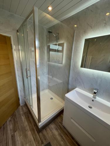 ein Bad mit einer Dusche und einem weißen Waschbecken in der Unterkunft Modern 4-bedroom entire house with Garden in Uxbridge