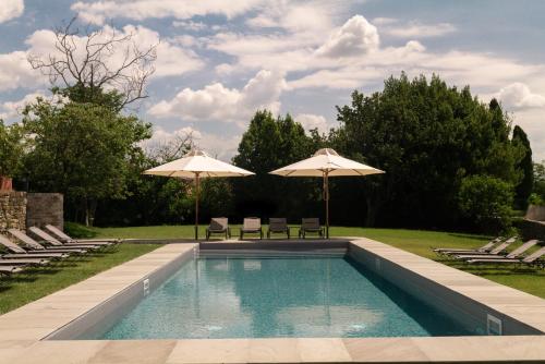 a swimming pool with two umbrellas and two chairs at Castello di Buttrio in Buttrio