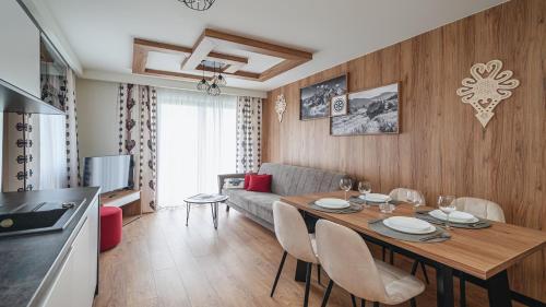 a kitchen and a living room with a table and chairs at Resorts L Białka Tatrzańska z sauną, Sun & Snow in Białka Tatrzanska