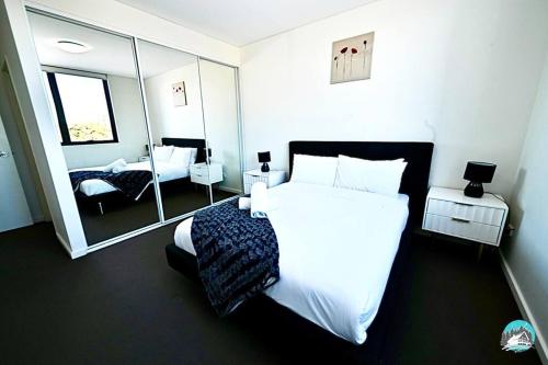 a bedroom with a large white bed and a mirror at Aircabin - Canterbury - Cheerful - 2 Bed Apartment in Sydney