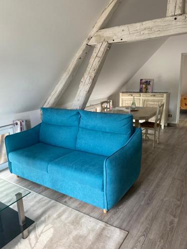 a blue couch in a living room with a table at Le Cosy de Roseline in Sézanne