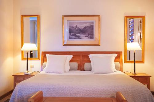 a bedroom with a large bed with two lamps at Le Saint Alexis **** Hotel & Spa in Saint-Gilles les Bains