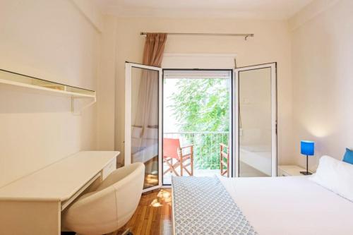 a bedroom with a bed and a desk and a balcony at Quiet Central apt in picturesque Pagrati in Athens