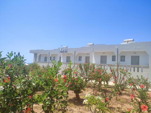 a white building with flowers in front of it at Keti Apartments in Adelianos Kampos