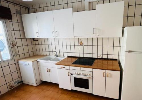 cocina con armarios blancos, fregadero y nevera en CASA LOS PILARES, en San Bartolomé de Pinares