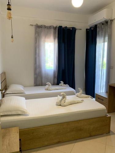 two beds in a room with blue curtains at Hotel Apostoli in Përmet