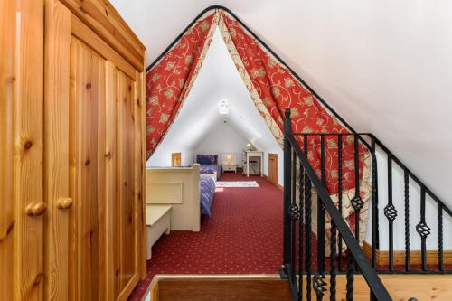 バリーコニーリーにあるCottage 207 - Ballyconneelyの赤いカーペットフロアの客室で、階段、ベッド1台が備わります。