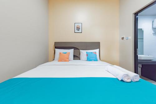 a bedroom with a large bed with orange and blue pillows at Sans Hotel Berau Square in Tanjungredep