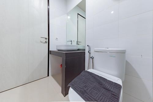a bathroom with a sink and a toilet and a mirror at Sans Hotel Berau Square in Tanjungredep
