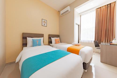 a bedroom with two beds and a window at Sans Hotel Berau Square in Tanjungredep