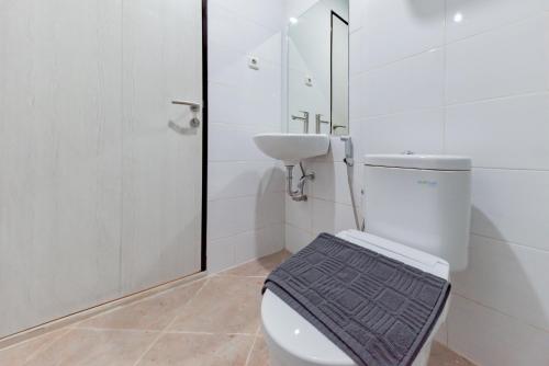 a white bathroom with a toilet and a sink at Sans Hotel Berau Square in Tanjungredep