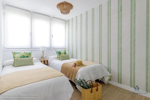 two beds in a room with green and white stripes at Living4malaga Mi Carmela Beach in Málaga
