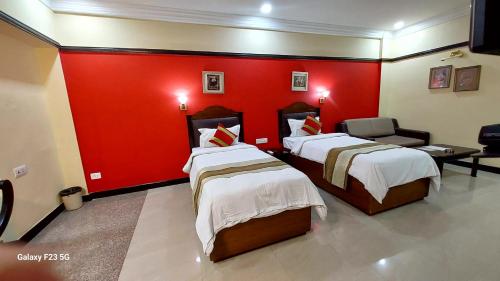 a room with two beds and a red wall at Lytton Hotel in Kolkata