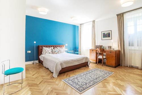 a bedroom with a blue wall and a bed and a desk at Garden View Apartment in Budapest