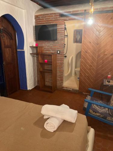 a bedroom with a bed and a television and towels at Riad Mauritania in Chefchaouene