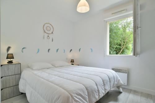 ein weißes Schlafzimmer mit einem großen Bett und einem Fenster in der Unterkunft Butterfly - Appartement avec jardin in Miniac-Morvan
