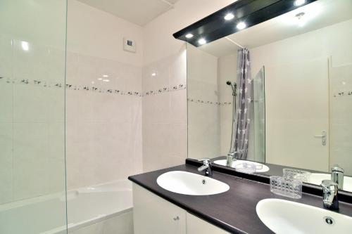 ein Badezimmer mit einem Waschbecken, einem Spiegel und einer Badewanne in der Unterkunft Butterfly - Appartement avec jardin in Miniac-Morvan