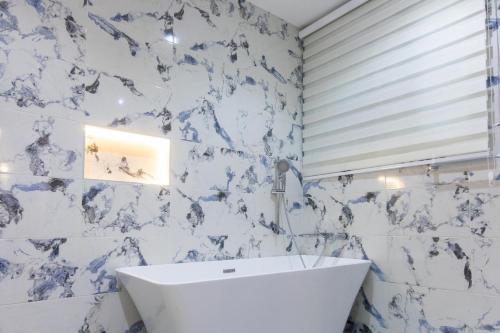 een badkamer met blauwe en witte marmeren muren en een wastafel bij Executive Studio Apartment, East Airport in Accra