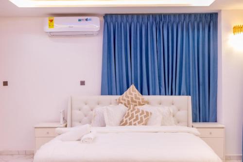 een slaapkamer met een wit bed en blauwe gordijnen bij Executive Studio Apartment, East Airport in Accra