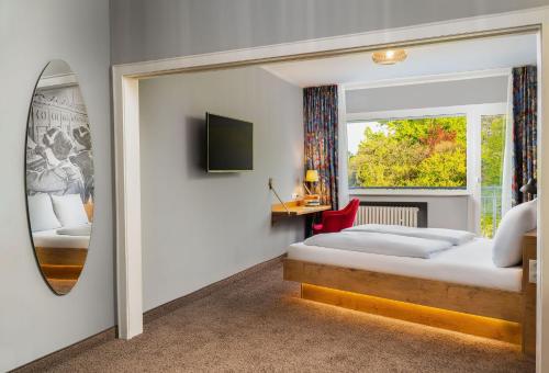 a bedroom with a bed and a mirror and a window at tinyTwice Hotel Bonn in Bonn