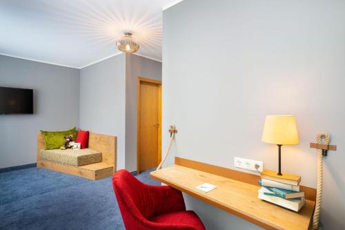 a room with a desk and a chair and a couch at tinyTwice Hotel Bonn in Bonn