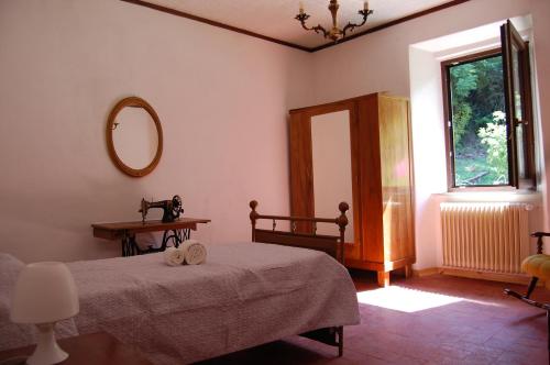 een slaapkamer met een bed, een spiegel en een raam bij Casa Millefiori in Bagni di Lucca