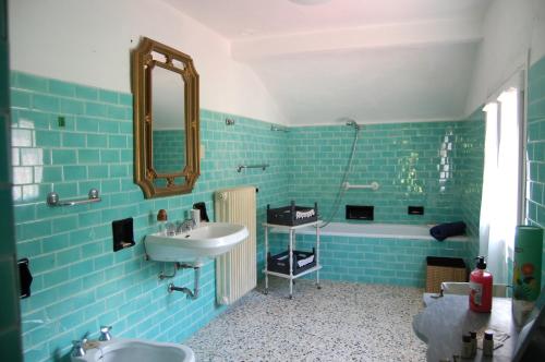 a blue tiled bathroom with a sink and a tub at Casa Millefiori in Bagni di Lucca