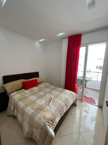 1 dormitorio con cama y cortina roja en Appartement de luxe, Tanagra Mall en Kenitra