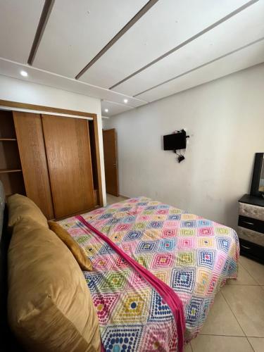 1 dormitorio con 1 cama y TV en la pared en Appartement de luxe, Tanagra Mall en Kenitra