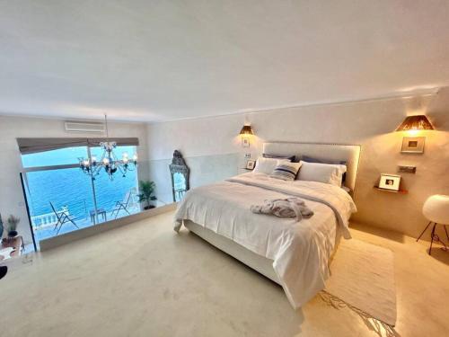 a bedroom with a large bed and a large window at The Cliff Appartment in Dar Mimoun Bey
