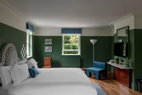 a bedroom with a white bed and green walls at Cowley Manor Experimental in Cheltenham