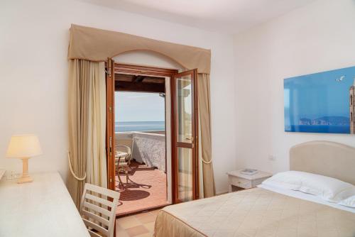 a bedroom with a bed and a view of the ocean at Hotel Punta Negra in Alghero