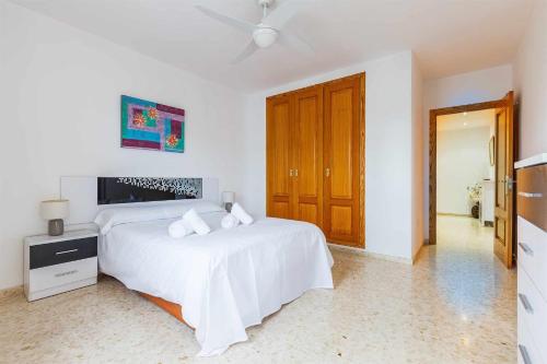 a white bedroom with a bed and a ceiling fan at Apartamento Azucarera Beach Torre del Mar in Torre del Mar