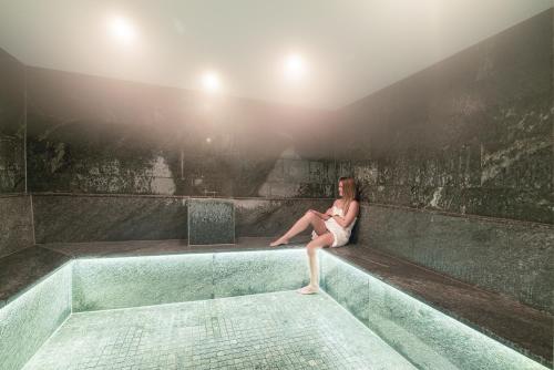 a woman sitting on the edge of a bath tub at Riffelalp Resort 2222m Ski-in & Ski-out in Zermatt