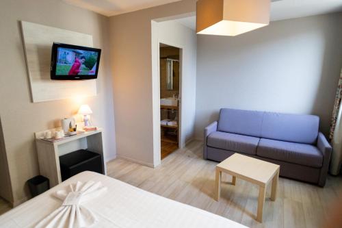 a living room with a blue couch and a tv at The Originals Boutique, Hôtel Neptune, Berck-sur-Mer (Inter-Hotel) in Berck-sur-Mer