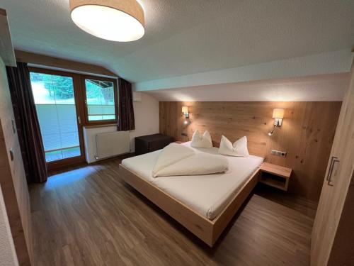 Schlafzimmer mit einem Bett mit weißer Bettwäsche und Kissen in der Unterkunft Appartementhaus Nadine in Längenfeld