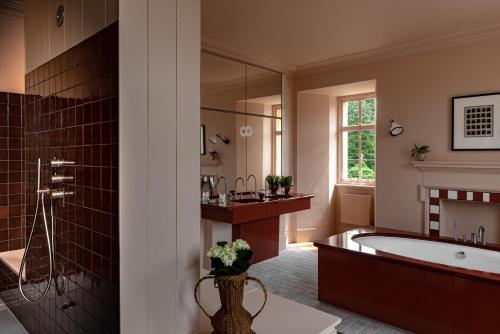 a bathroom with a tub and a large mirror at Cowley Manor Experimental in Cheltenham