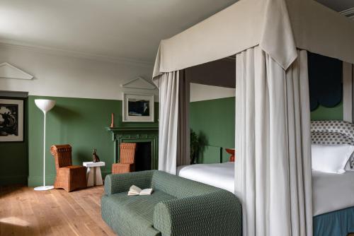 a bedroom with a canopy bed with a green wall at Cowley Manor Experimental in Cheltenham