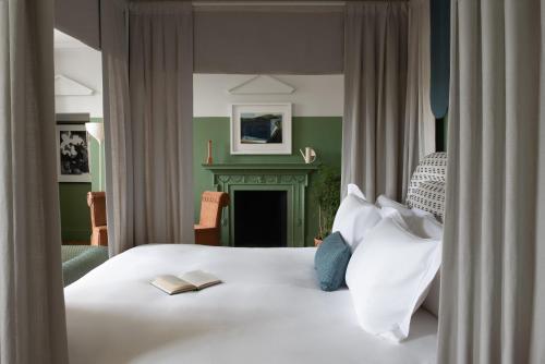 a bedroom with a white bed and a fireplace at Cowley Manor Experimental in Cheltenham