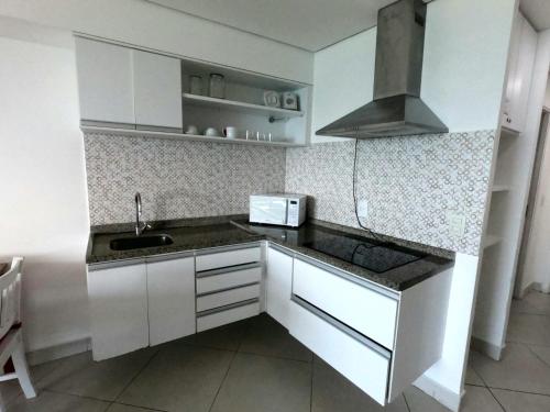 una pequeña cocina con armarios blancos y fregadero en Fortaleza VIP Experience, en Fortaleza