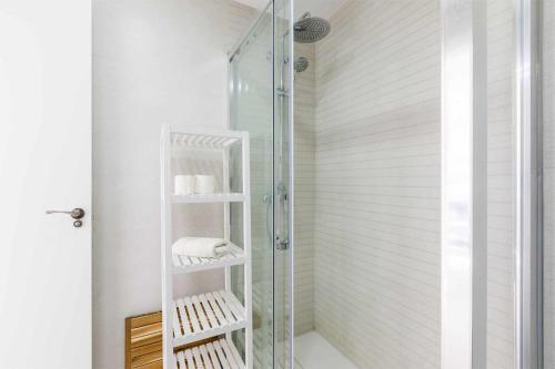La salle de bains est pourvue d'une douche en verre et de serviettes sur les étagères. dans l'établissement A&N Seafront Torre del Mar, à Torre del Mar